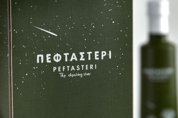 A green cardboard box of olive oil. A shooting star is tracing on the top, with the words Peftasteri - The Shooting Star inscribed.